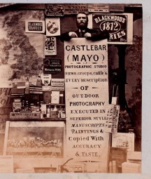 Sepia photograph of a man holding a large sign advertising his Photographic Studio in Castlebar, Co.Mayo