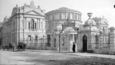 A black and white photo of the National Library of Ireland's buildings at Kildare Street with two horse and carts on the streets outside