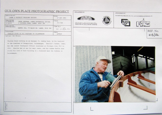 A card from the Our Own Place Photographic Project (taken on Wednesday, 27 October 1993 at 10.15am) showing Charlie Stitt working on an Oarsman 15 rowing boat, in his boatyard in the townland of Drumgurland, Islandmagee, Co. Antrim